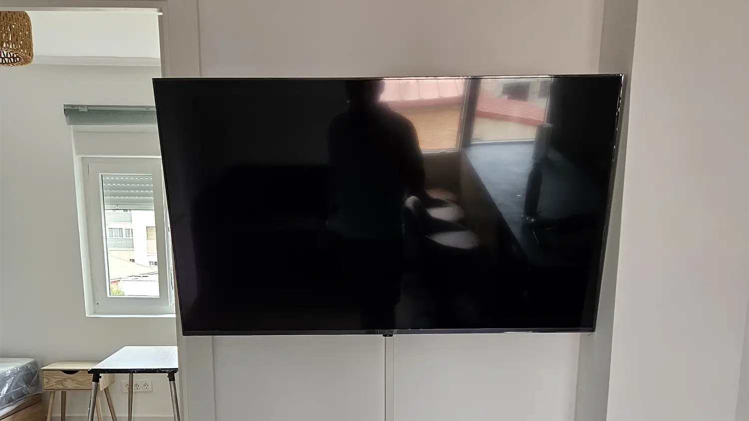 Televisor de pantalla plana instalado en la pared de un salón moderno.